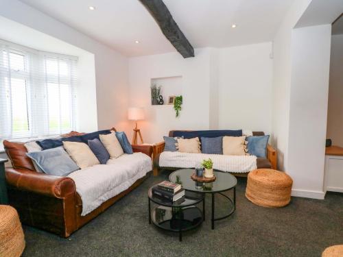 a living room with two couches and a table at Broad Beams in Neston