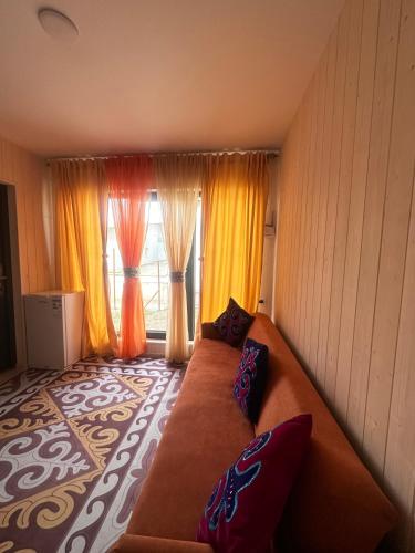 a living room with a couch in front of a window at EL House in Karakol