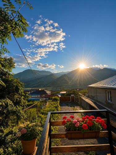 a view of the sun from a balcony with flowers at Relax Kazbegi Panoramic Mountain View in Kazbegi