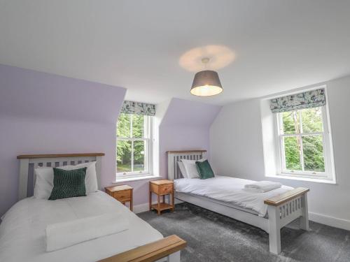 two beds in a room with two windows at Station Lodge in Forres