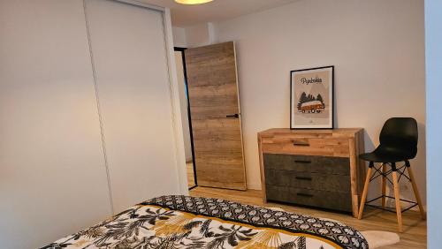 a bedroom with a bed and a dresser and a chair at Appartement cozy 2 chambres in Luchon