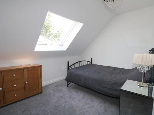 a bedroom with a bed and a dresser and a window at Lucerne Cottage in Dorking