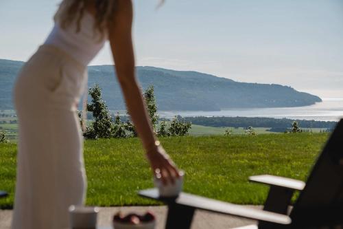 a woman in a white dress looking out over a field at 102 - Upscale Condo - River View Terrace in Baie-Saint-Paul