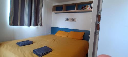 a bedroom with a yellow bed with two blue pillows at Mobilhome 217 in Torreilles