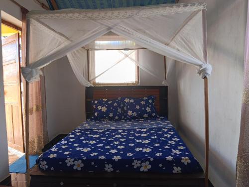 a bed with a canopy in a room with a window at FG Bungalow Bar in Ianakandrarezo