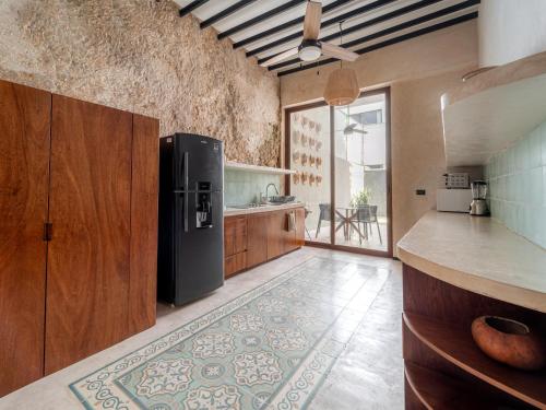 a kitchen with a black refrigerator and wooden cabinets at Casa Bolero Santa Lucía with Parking by Cercana in Mérida