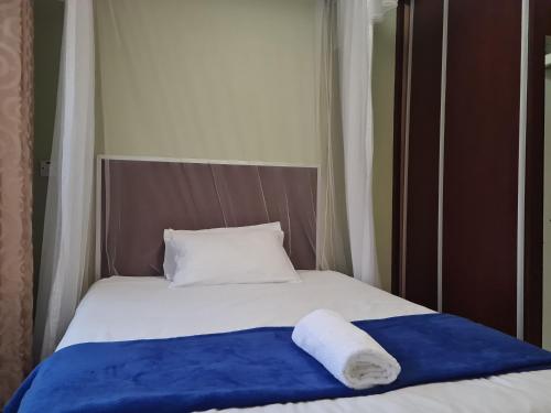 a bed with a blue blanket and a white pillow at The Cottage in Lilongwe