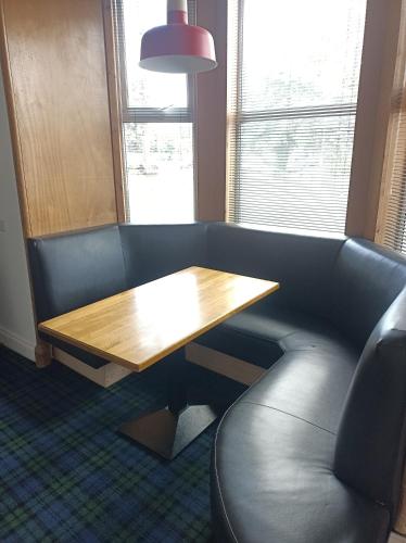 a booth with a wooden table and a leather chair at The Townhouse Self Catering in Dumfries