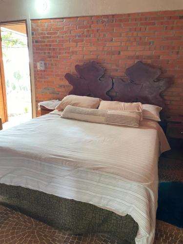 a bedroom with a large bed with a brick wall at Villa Virgen De La Gracia in Tobatí