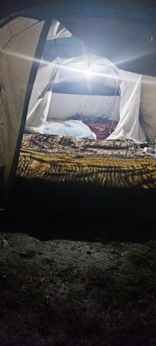 a bed inside of a tent with the light on at eco friendly camping site pahalgam in Pahalgām