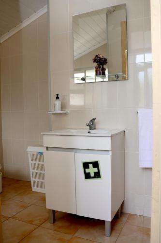 a white bathroom with a sink and a mirror at Recanto do Capucho in Conceição