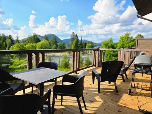 a deck with a table and chairs and a grill at Condo by the Lake - Mountain View & Resort in Lac-Superieur