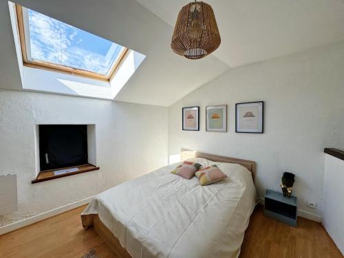 a bedroom with a bed with a television and a window at La Palmeraie, Duplex in Bar-le-Duc