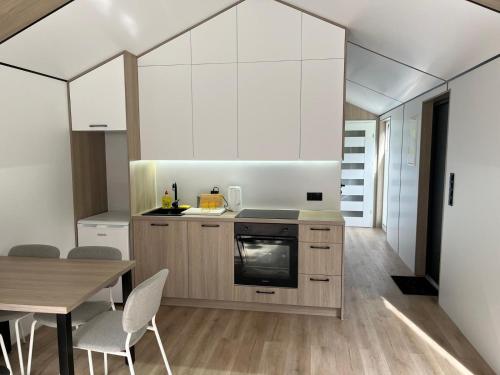 a kitchen with white cabinets and a table with chairs at Domek pod brzozami in Waszki