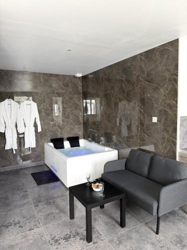 a bath tub in a room with a couch and clothes at Rochetaillée Secret Spa in Saint-Étienne