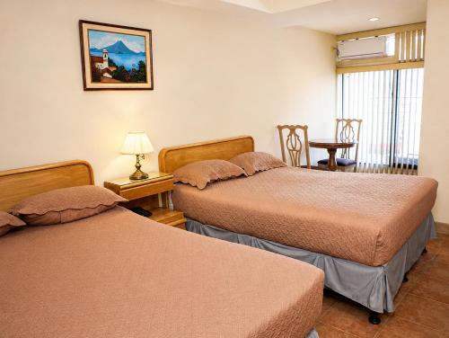 a room with two beds and a table with a chair at Hotel Bresciani in La Aurora