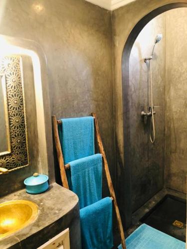 a bathroom with a sink and a shower with blue towels at Villa Azal in Mirleft