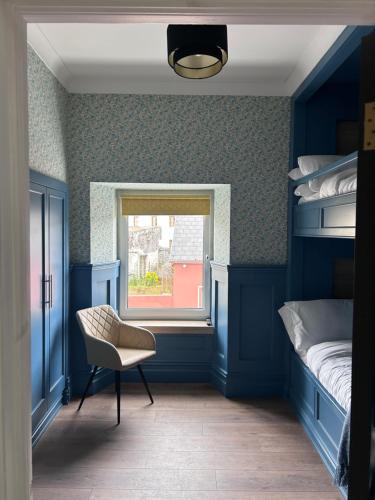 a bedroom with blue walls and a chair and a window at Creagh Road House in Ballinrobe