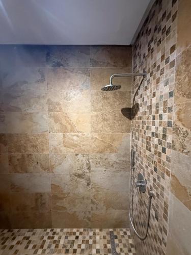 a bathroom with a shower with a tiled wall at Aouina Stay in El Aouina Station