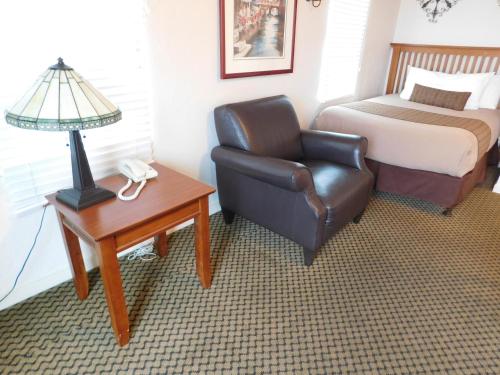 a bedroom with a bed and a chair and a lamp at Capitola Venetian Vacation Rentals in Capitola