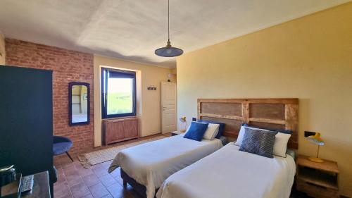 a bedroom with two beds and a window at Ca' Sinoira in Nizza Monferrato