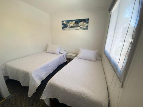 two beds in a room with a window at Amoblados Copiapo in Copiapó