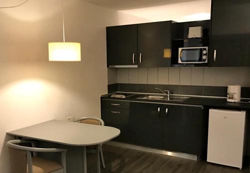 a kitchen with black cabinets and a table and a sink at Almar Hotel Apartamento in Albufeira