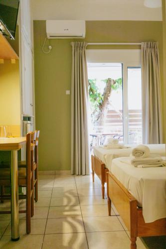 a room with two beds and a table and a window at Anna Christina in Kamena Vourla