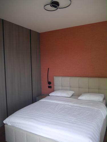 a bedroom with a large white bed with a red wall at Apartment Marta Tivat in Tivat