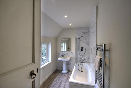 a white bathroom with a tub and a sink at Abbey House by Group Retreats in Saffron Walden