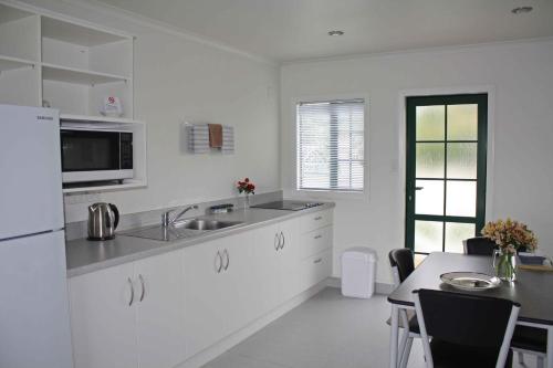 a white kitchen with a sink and a table at Kerry Lane Motel in Hawera