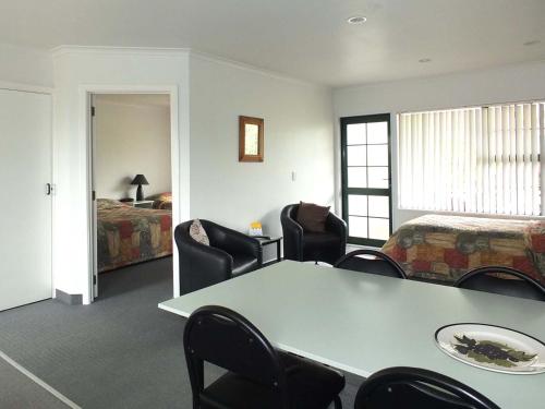 a room with a table and chairs and a bed at Kerry Lane Motel in Hawera