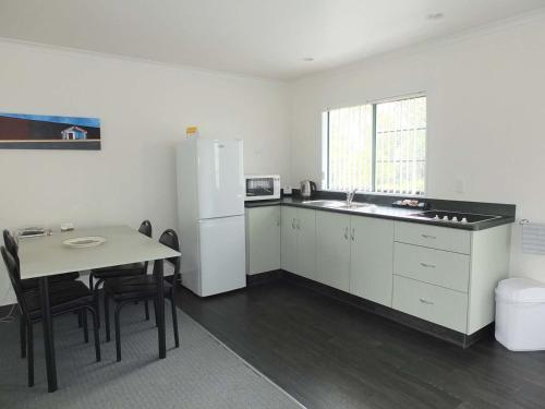 a kitchen with a table and a white refrigerator at Kerry Lane Motel in Hawera