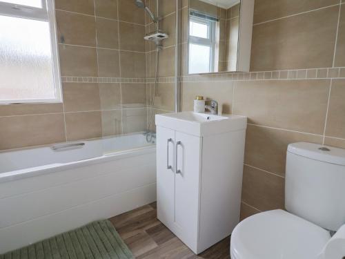 a bathroom with a toilet and a sink and a tub at Hazelwood 3 in Lyme Regis