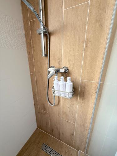 a shower with three white bottles sitting on a shelf at Sarah Doe Apartman in Nyíregyháza