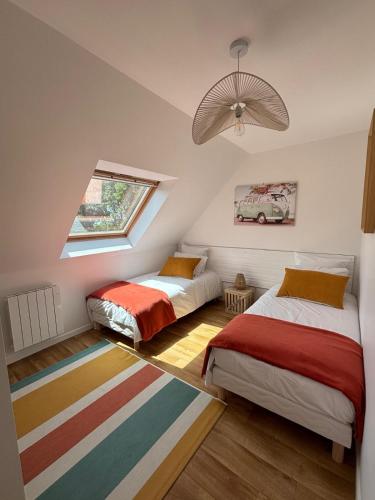 a attic bedroom with two beds and a window at Résidence de la Presqu'île in Plougonvelin