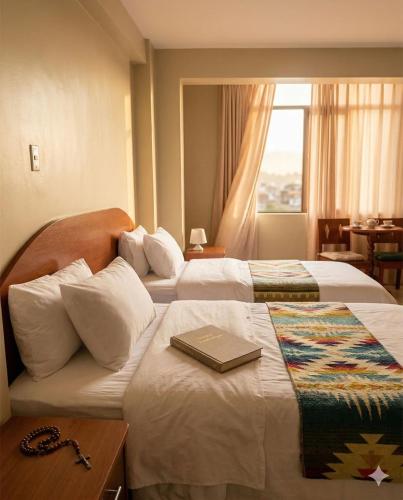 a hotel room with two beds with a book on it at Hotel INTERnazionale in Ayacucho
