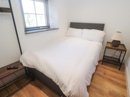 a bedroom with a large bed with white sheets at Gews Farm Lodge in Penzance