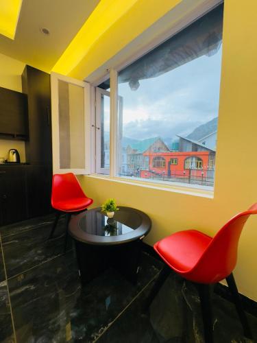 a room with two red chairs and a table and a window at Arkay Sonamarg in Sonāmarg