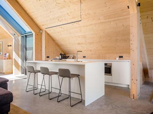 a kitchen with a white counter and stools at Villa WOOD in Elsendorp