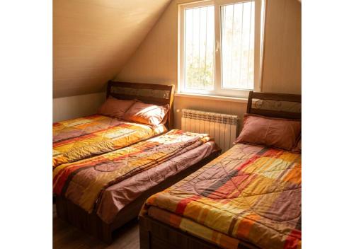 two beds in a room with two windows at Forest Edge Guesthouse in Aghavnadzor