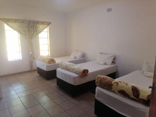 a room with three beds and a couch at Royal Oasis in Mahikeng