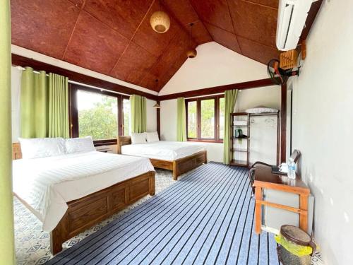 a bedroom with two beds and a table and windows at L'Ananas Garden Homestay in Vũ Lâm