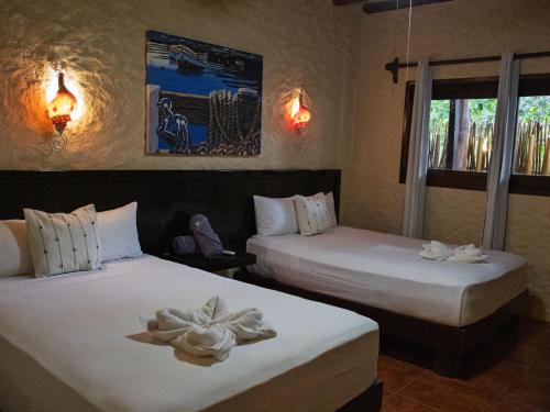 a bedroom with two beds with white sheets at Chuk-Kay by ÓOL Hotels in Holbox Island