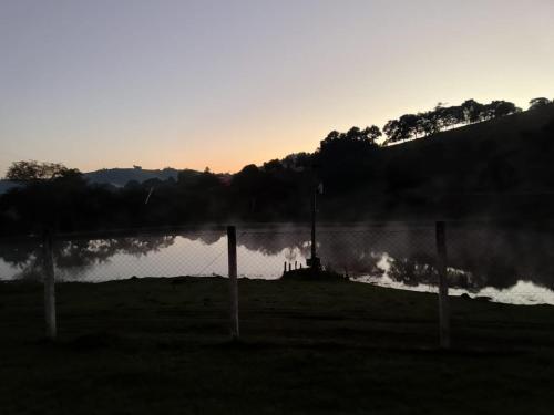 a view of a lake at sunset with a fence at Recanto 2 irmãos in Socorro