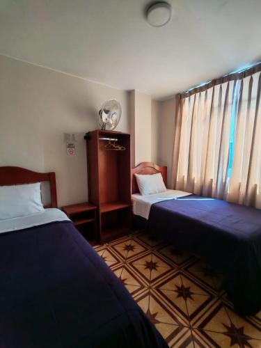a room with two beds and a fan and curtains at Hallpa Ica in Ica