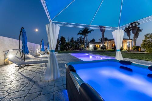 a swimming pool with umbrellas and a house at Villa Cassandra in Alliste