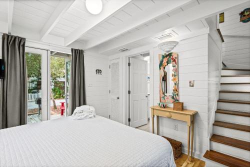a white bedroom with a bed and a mirror at Margarita Days in Seagrove Beach
