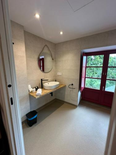 ein Badezimmer mit Waschbecken und roter Tür in der Unterkunft Casa Cando in Castroverde