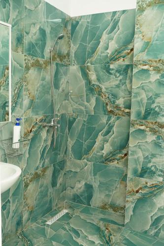 a bathroom with a shower with blue tiles at Corner Apartments in Tirana